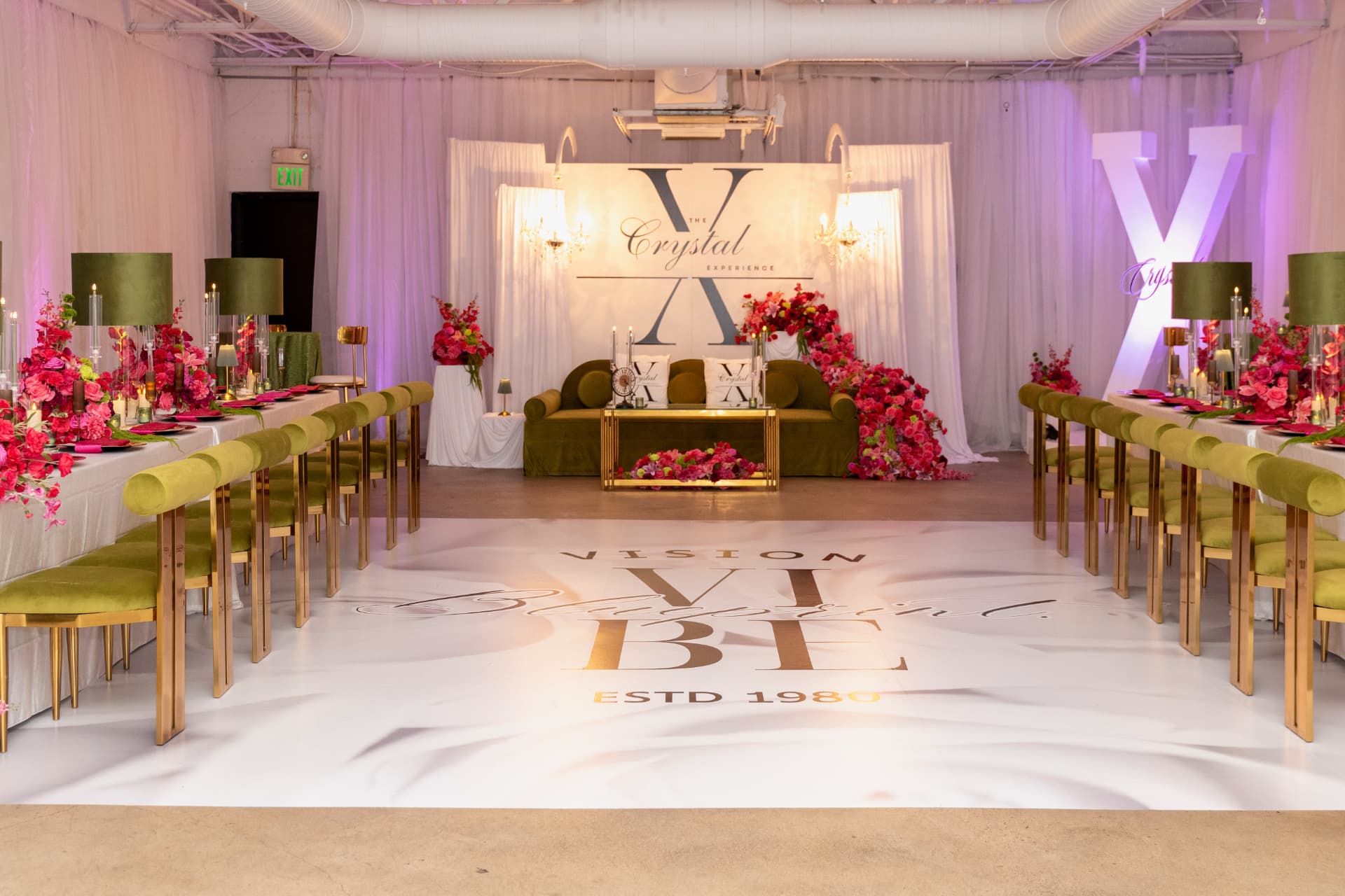 Realised presidium with monogram backdrop, olive velvet sofa, printed floor and pink florals